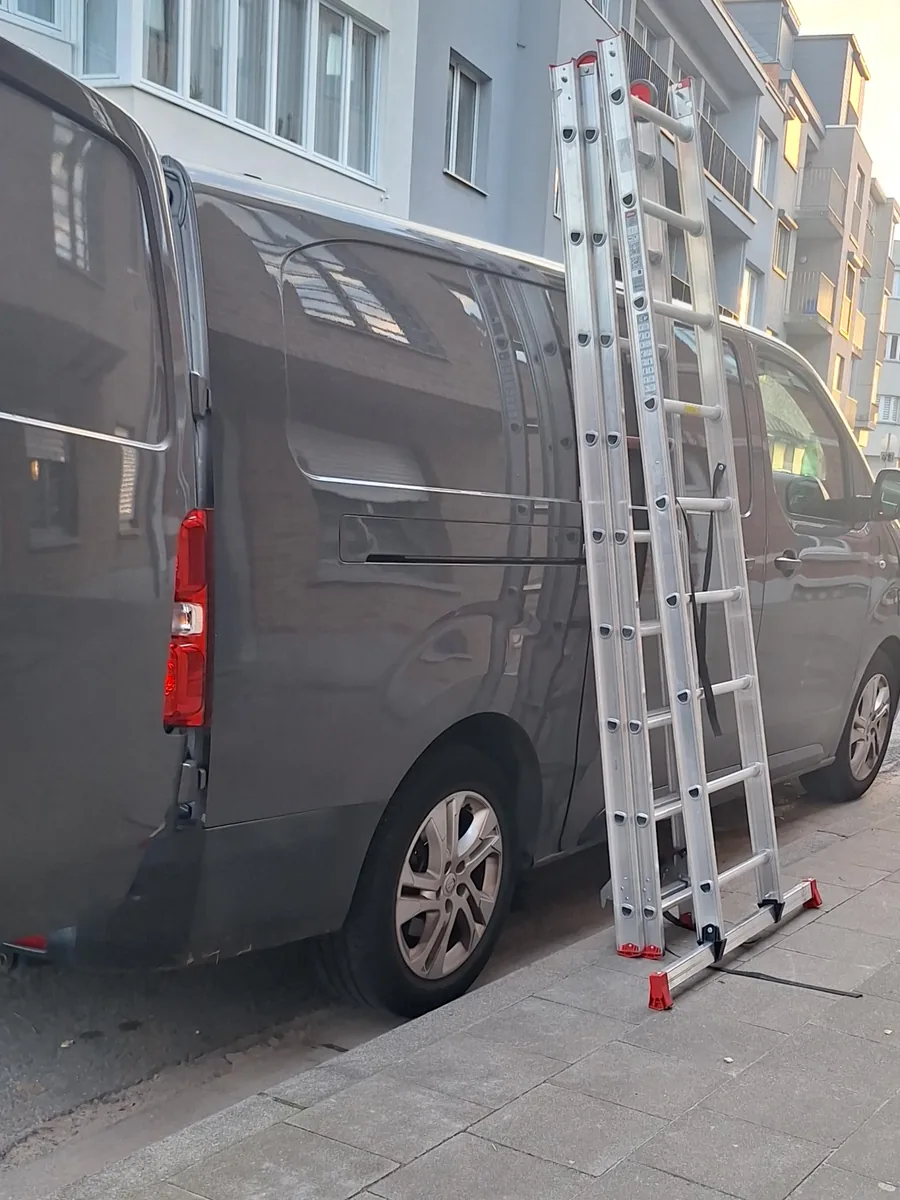 Échelle en aluminium appuyée contre notre camionnette, sur le trottoir, et non contre la façade de l'immeuble.