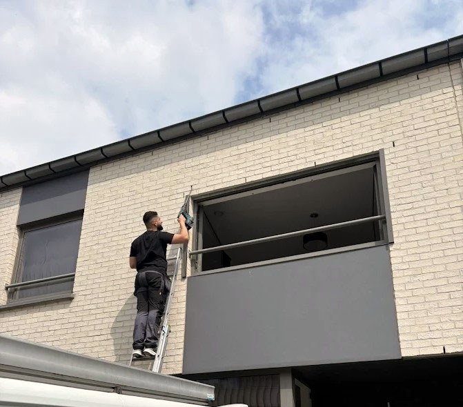 Technicien Vandernoot Volet en hauteur sur échelle lors de l'installation d'un volet roulant à Uccle — mai 2026
